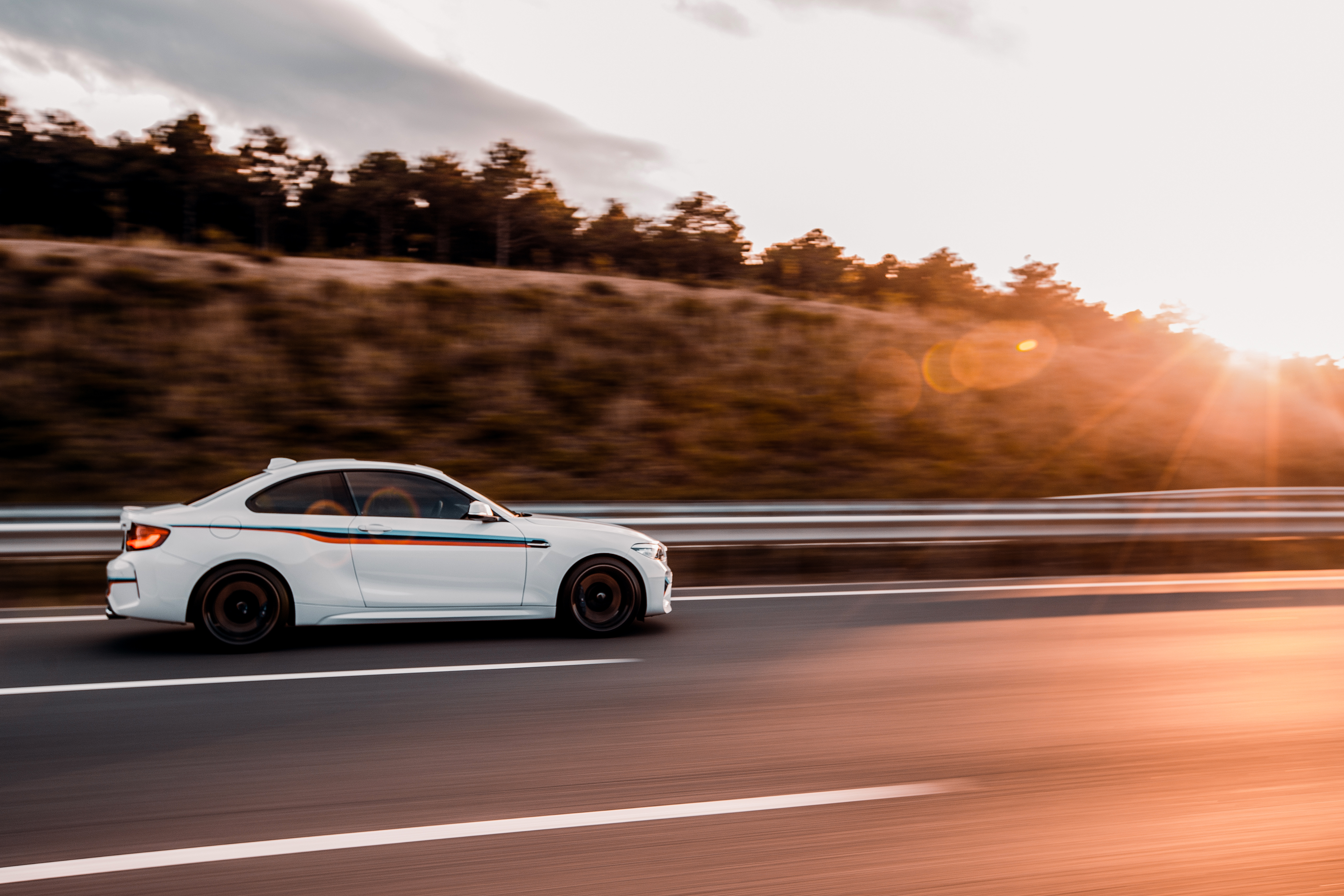 white coupe sedan driving road sunset